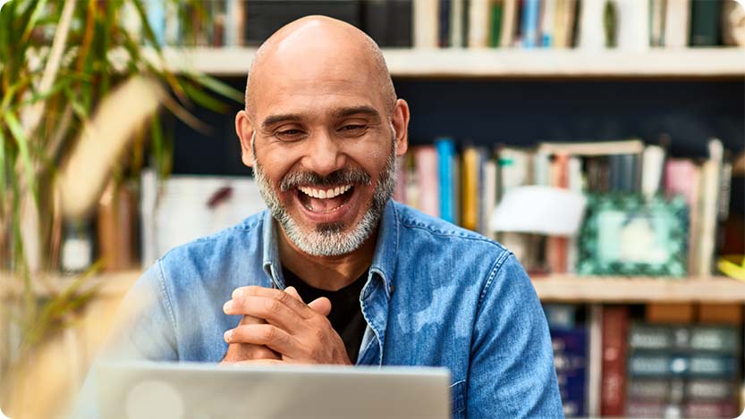 Person smiling while using a laptop at home.